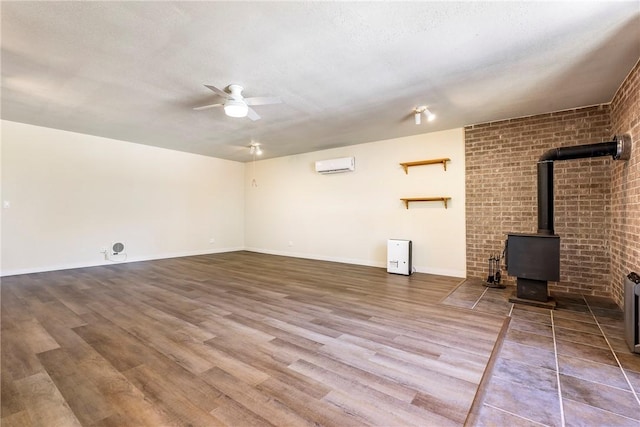 19051 Pinecrest Ln, Rogers, AR 72756 - unfurnished living room featuring a wall unit AC, a wood stove, ceiling fan, and wood finished floors