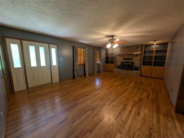 208 Mc 6087, Yellville, AR 72687 - unfurnished living room featuring a textured ceiling, wood finished floors, a ceiling fan, and a fireplace