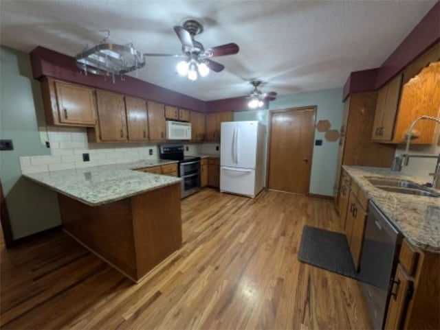 208 Mc 6087, Yellville, AR 72687 - kitchen featuring stainless steel appliances, brown cabinetry, a peninsula, a sink, and light wood finished floors