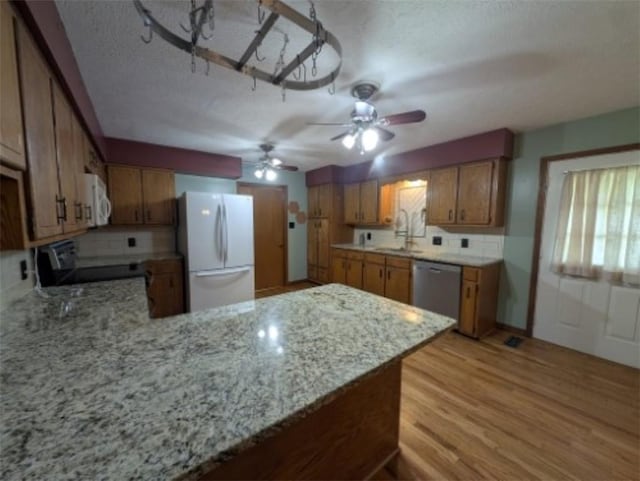 208 Mc 6087, Yellville, AR 72687 - kitchen featuring white appliances, brown cabinets, a peninsula, a sink, and light wood-style floors