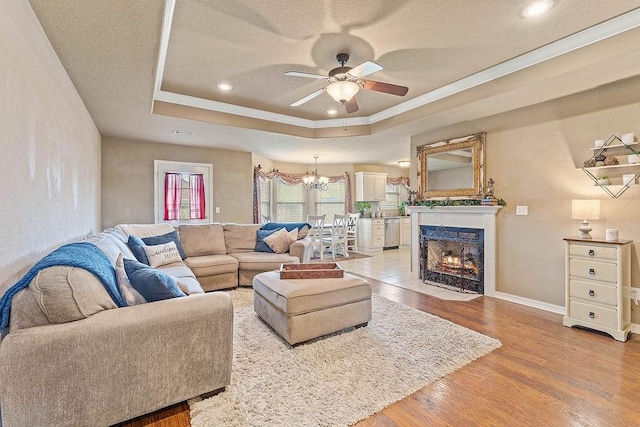 801 SW Castlewood St, Bentonville, AR 72712 - living area featuring a ceiling fan, a tray ceiling, a chandelier, a textured ceiling, and light wood-type flooring