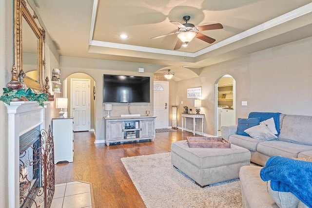 801 SW Castlewood St, Bentonville, AR 72712 - living area featuring arched walkways, washer and clothes dryer, ceiling fan, a raised ceiling, and wood finished floors