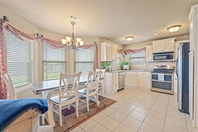 801 SW Castlewood St, Bentonville, AR 72712 - kitchen with appliances with stainless steel finishes, a chandelier, light tile patterned flooring, a textured ceiling, and pendant lighting