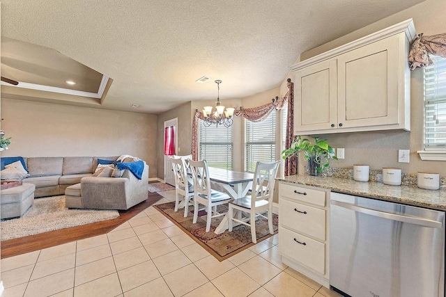 801 SW Castlewood St, Bentonville, AR 72712 - kitchen with stainless steel dishwasher, open floor plan, a chandelier, light tile patterned floors, and light stone counters