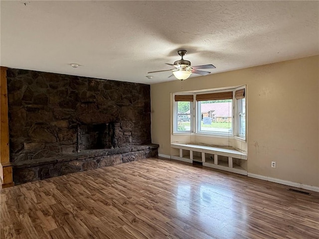 1902 W Granite St, Siloam Springs, AR 72761 - unfurnished living room featuring a ceiling fan, wood finished floors, baseboards, a textured ceiling, and a fireplace
