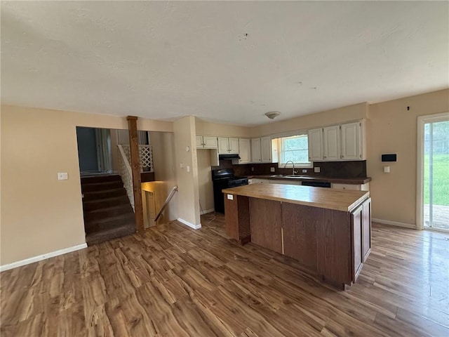 1902 W Granite St, Siloam Springs, AR 72761 - kitchen featuring butcher block counters, wood finished floors, white cabinetry, baseboards, and healthy amount of natural light