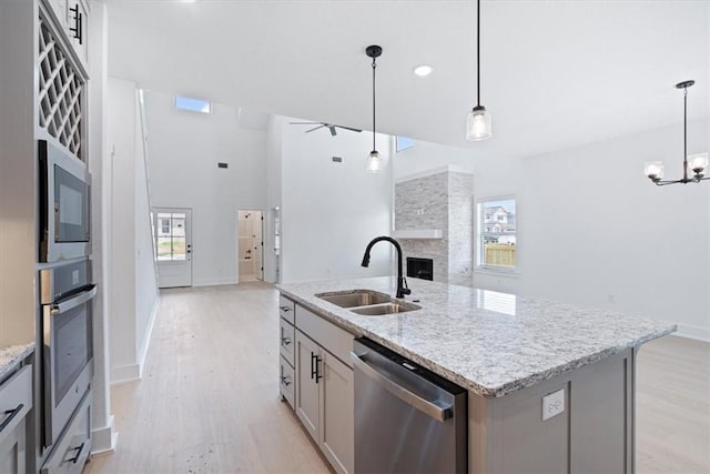 7101 SW Basswood Ave, Bentonville, AR 72713 - kitchen featuring stainless steel appliances, a sink, open floor plan, light wood-style floors, and a fireplace