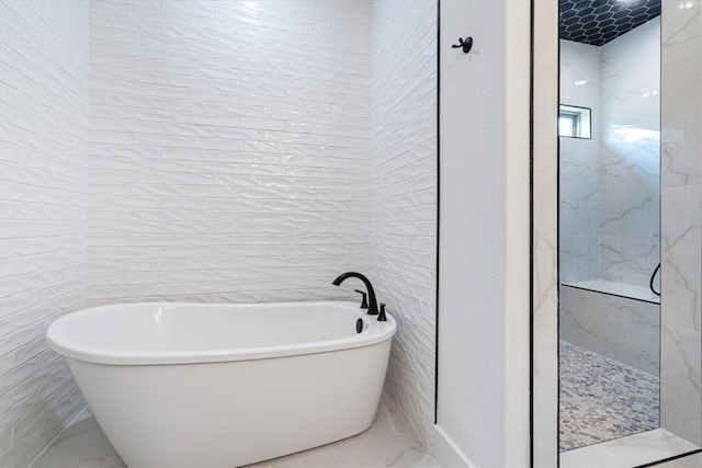 7101 SW Basswood Ave, Bentonville, AR 72713 - full bathroom featuring marble look tile flooring, a freestanding tub, tile walls, and a marble finish shower