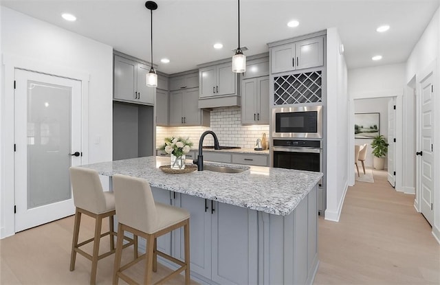 7101 SW Basswood Ave, Bentonville, AR 72713 - kitchen with gray cabinets, a sink, stainless steel appliances, backsplash, and light stone counters