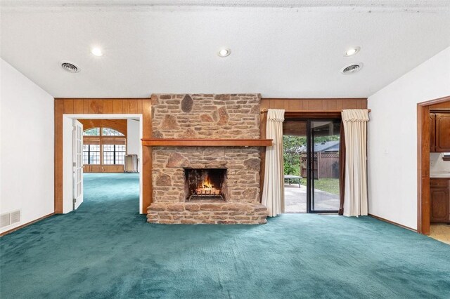 1719 Ridgeview Dr, Springdale, AR 72762 - unfurnished living room with carpet floors, wood walls, a stone fireplace, and baseboards