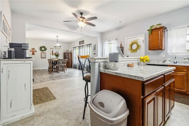 1017 Richland Creek Ave, Elkins, AR 72727 - kitchen featuring light countertops, a kitchen island, ceiling fan, brown cabinets, and hanging light fixtures