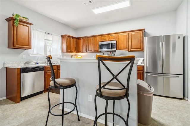 1017 Richland Creek Ave, Elkins, AR 72727 - kitchen featuring stainless steel appliances, brown cabinetry, light countertops, and a kitchen island