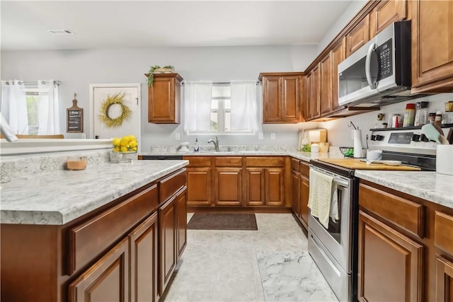 1017 Richland Creek Ave, Elkins, AR 72727 - kitchen featuring appliances with stainless steel finishes, brown cabinets, a sink, and light stone countertops