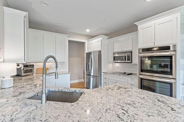 1000 Halifax Pl, Bentonville, AR 72712 - kitchen with appliances with stainless steel finishes, a sink, recessed lighting, white cabinetry, and light stone countertops