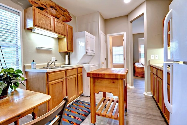 811 E Township St, Fayetteville, AR 72703 - kitchen with estacked washer and dryer, a sink, light wood-style flooring, and freestanding refrigerator