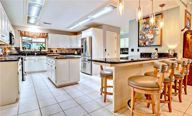 811 E Township St, Fayetteville, AR 72703 - kitchen with black microwave, white cabinets, tasteful backsplash, a peninsula, and light tile patterned flooring