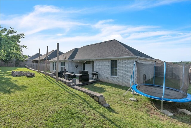 1461 Colonel Mcneil Dr, Prairie Grove, AR 72753 - rear view of property featuring a trampoline, brick siding, a shingled roof, and a patio area