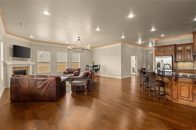 3504 NW Edgewood Ave, Bentonville, AR 72712 - living room with a chandelier, dark wood finished floors, baseboards, ornamental molding, and a lit fireplace