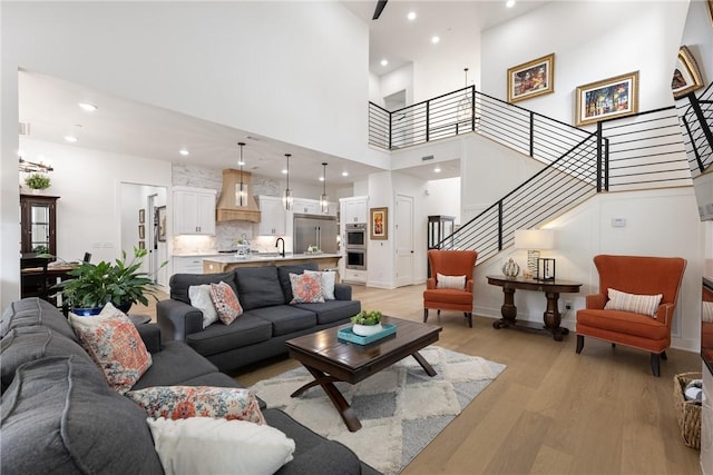 301 SW Autumn Hills Rd, Bentonville, AR 72712 - living room featuring light wood finished floors, stairs, a towering ceiling, and recessed lighting