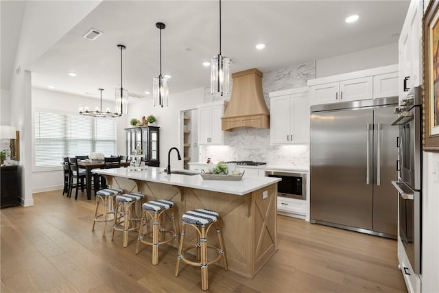 301 SW Autumn Hills Rd, Bentonville, AR 72712 - kitchen with built in appliances, a sink, custom exhaust hood, light wood finished floors, and decorative backsplash