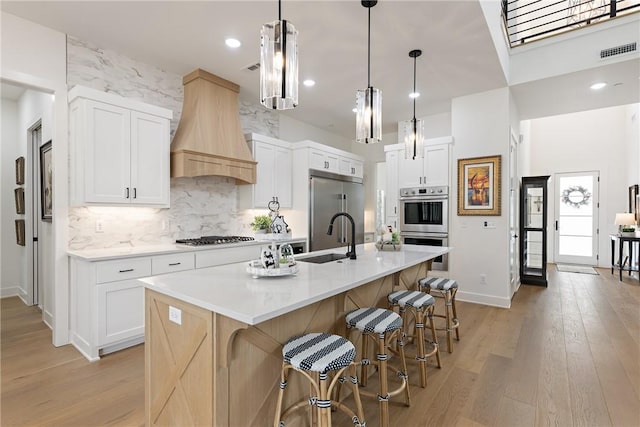 301 SW Autumn Hills Rd, Bentonville, AR 72712 - kitchen with custom exhaust hood, stainless steel appliances, a sink, light wood finished floors, and a breakfast bar area