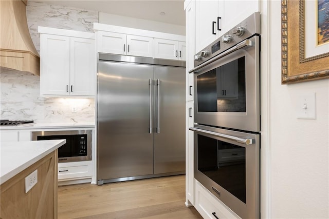 301 SW Autumn Hills Rd, Bentonville, AR 72712 - kitchen featuring built in appliances, light wood-style floors, light countertops, and white cabinets