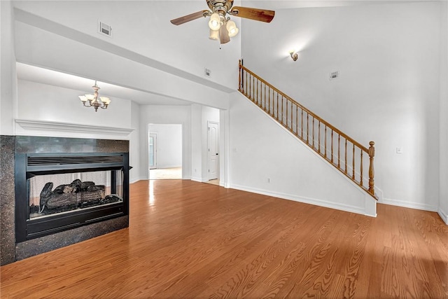 4801 SW Golden Eagle Ave, Bentonville, AR 72713 - unfurnished living room with ceiling fan, wood finished floors, stairway, a chandelier, and a high ceiling