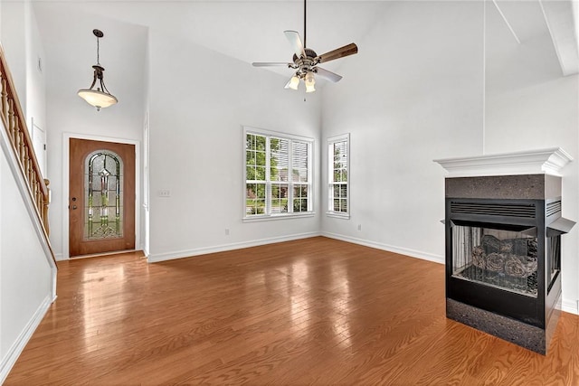 4801 SW Golden Eagle Ave, Bentonville, AR 72713 - unfurnished living room with ceiling fan, stairway, wood finished floors, a towering ceiling, and baseboards
