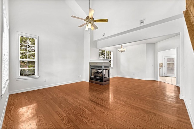 4801 SW Golden Eagle Ave, Bentonville, AR 72713 - unfurnished living room featuring high vaulted ceiling, wood finished floors, a multi sided fireplace, a ceiling fan, and baseboards