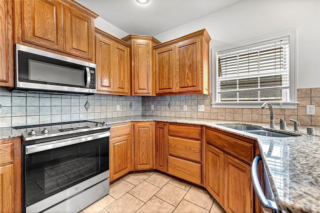 4801 SW Golden Eagle Ave, Bentonville, AR 72713 - kitchen with appliances with stainless steel finishes, a sink, tasteful backsplash, light stone counters, and brown cabinetry