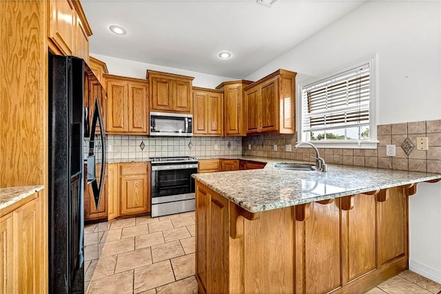 4801 SW Golden Eagle Ave, Bentonville, AR 72713 - kitchen featuring stainless steel appliances, a peninsula, a sink, backsplash, and a breakfast bar area