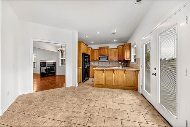 4801 SW Golden Eagle Ave, Bentonville, AR 72713 - kitchen with stainless steel microwave, freestanding refrigerator, a peninsula, decorative backsplash, and light countertops
