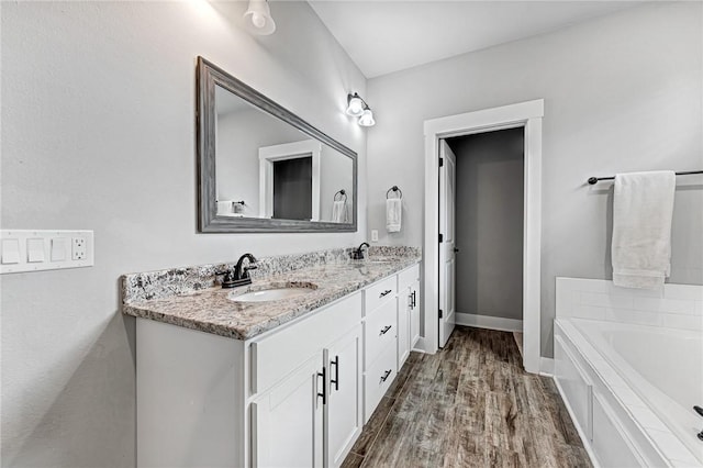 1140 Durante St, Tontitown, AR 72762 - bathroom featuring double vanity, a bath, wood finished floors, and baseboards