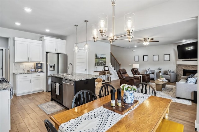 201 Ryder St, Gentry, AR 72734 - dining room featuring a ceiling fan, recessed lighting, light wood-style flooring, stairway, and a fireplace