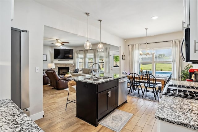 201 Ryder St, Gentry, AR 72734 - kitchen with a sink, stainless steel dishwasher, ceiling fan, a fireplace, and light wood-style floors