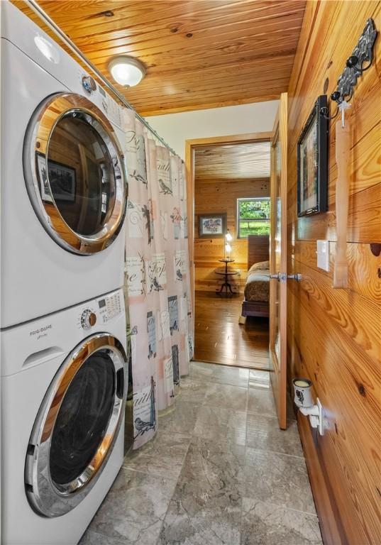482 County Road 332, Eureka Springs, AR 72632 - laundry area featuring wood ceiling, stacked washing machine and dryer, and wooden walls