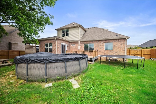 1320 Lariat Dr, Centerton, AR 72719 - rear view of property with a trampoline, brick siding, and a shingled roof