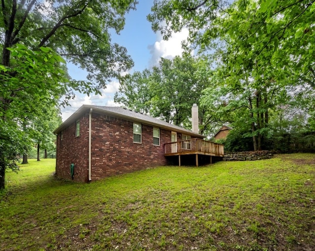 12305 Tyson Rd, Lowell, AR 72745 - back of house featuring a yard, a wooden deck, brick siding, and a chimney
