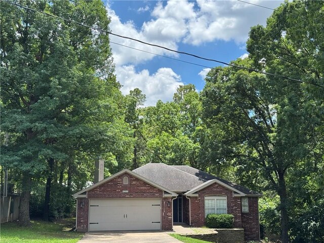 12305 Tyson Rd, Lowell, AR 72745 - view of front of property featuring brick siding, a garage, driveway, and a chimney