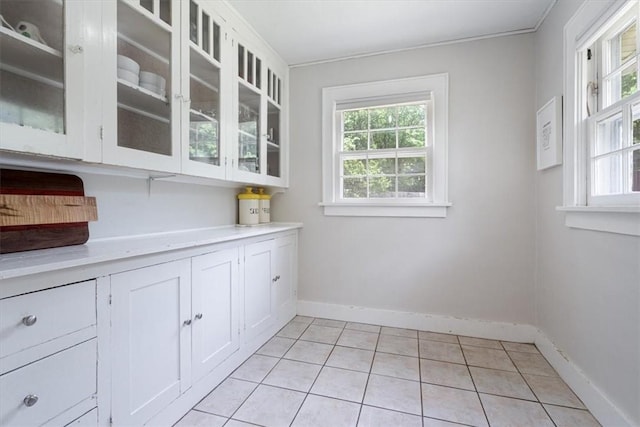 626 Ash St, Fayetteville, AR 72703 - kitchen featuring light countertops, glass insert cabinets, white cabinetry, light tile patterned floors, and baseboards