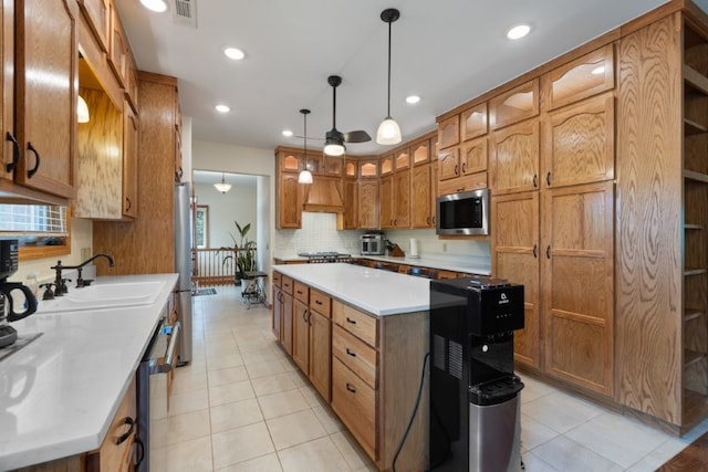 4 Torrido Ln, Bella Vista, AR 72715 - kitchen featuring a sink, stainless steel appliances, a kitchen island, brown cabinetry, and light tile patterned floors