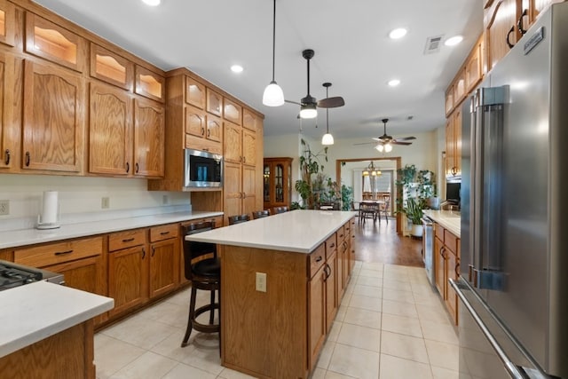 4 Torrido Ln, Bella Vista, AR 72715 - kitchen featuring stainless steel appliances, a center island, brown cabinets, ceiling fan, and light countertops