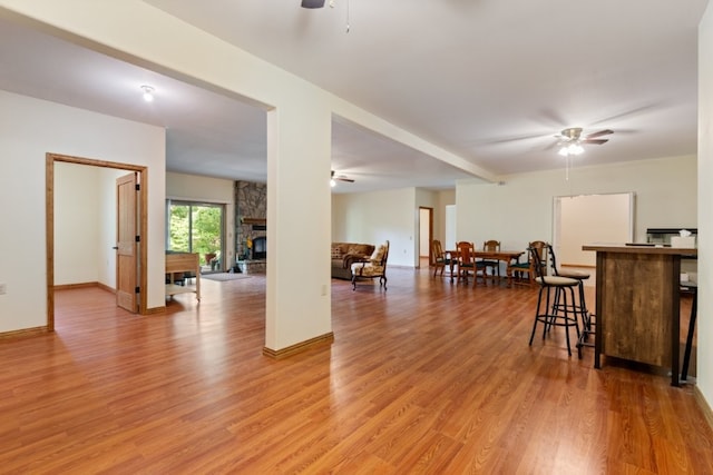 4 Torrido Ln, Bella Vista, AR 72715 - kitchen featuring a ceiling fan, light wood-type flooring, a stone fireplace, and baseboards