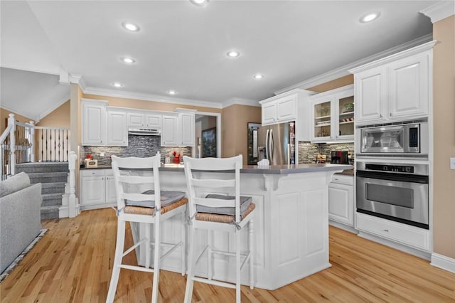 7 W Leiston Dr, Rogers, AR 72758 - kitchen featuring stainless steel appliances, decorative backsplash, ornamental molding, a kitchen bar, and white cabinets