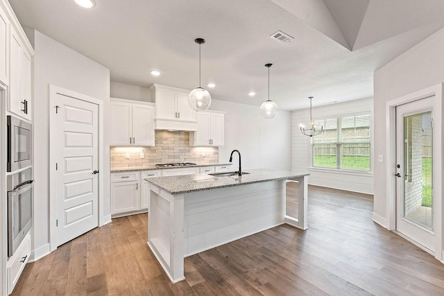 901 Carlock Dr, Pea Ridge, AR 72751 - kitchen featuring a sink, appliances with stainless steel finishes, light stone countertops, wood finished floors, and an island with sink