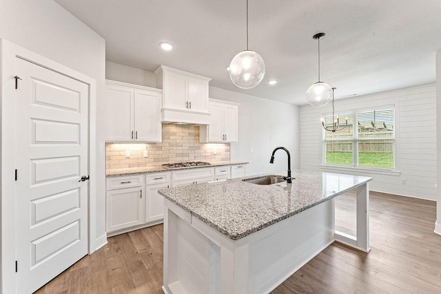 901 Carlock Dr, Pea Ridge, AR 72751 - kitchen featuring a sink, light wood-style flooring, decorative backsplash, white cabinetry, and a center island with sink