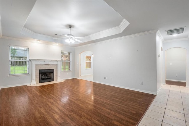 301 Halleck Coach Rd, Centerton, AR 72719 - unfurnished living room featuring arched walkways, a ceiling fan, a raised ceiling, ornamental molding, and a tile fireplace