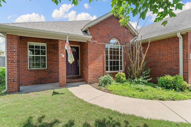 1750 Lancaster Dr, Springdale, AR 72762 - view of exterior entry with roof with shingles, brick siding, and a lawn