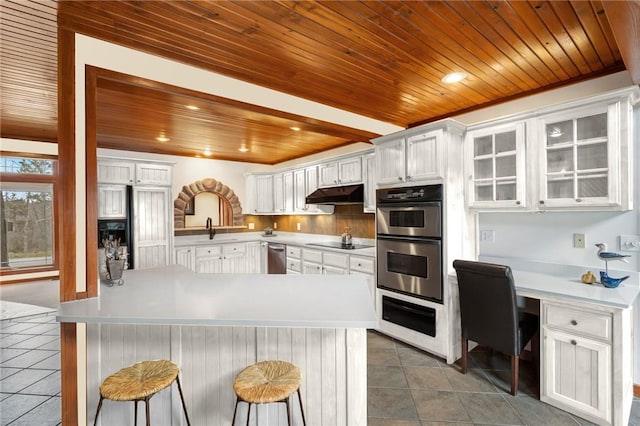 8093 Rockwood Ln, Rogers, AR 72756 - kitchen featuring stainless steel appliances, wooden ceiling, tile patterned flooring, under cabinet range hood, and a breakfast bar area
