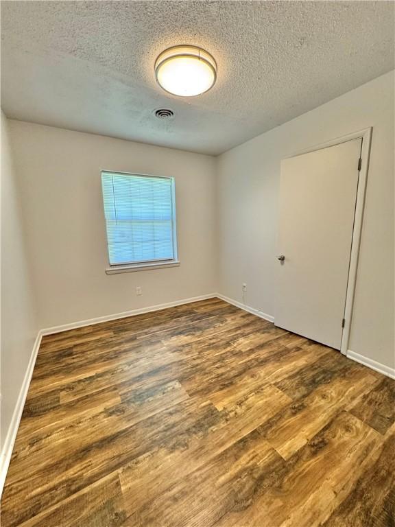 29 5th Ave, Dardanelle, AR 72834 - unfurnished room featuring wood finished floors, a textured ceiling, and baseboards